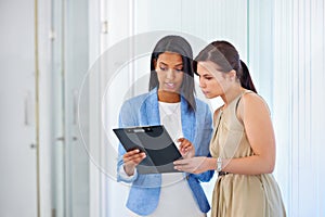 Lets talk and walk. a two young businesswomen discussing paperwork.