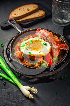 Letscho - tasty Hungarian vegetable stew with peppers, tomatoes and onions, served with bacon and fried egg