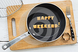 Letter biscuits word HAPPY WEEKEND and cooking equipments.