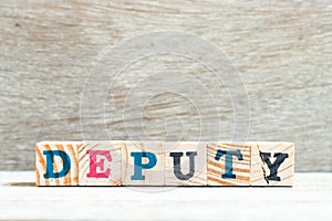Letter block in word deputy on wood background