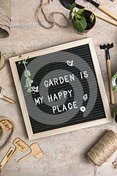 Letter board with text Garden is my happy place. Planting seeds in Biodegradable paper eco-friendly seed pots. Garden shovel and