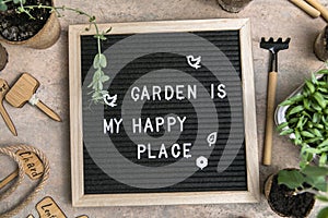 Letter board with text Garden is my happy place. Planting seeds in Biodegradable paper eco-friendly seed pots. Garden shovel and