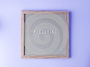 Letter board with word saying Fidgeting on purple