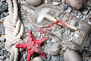 Letter in bottle on stones with starfish and marine knot