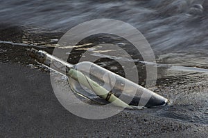 A letter in a bottle thrown into the sand by the sea waves selective focus