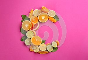 Letter C made with citrus fruits on pink background as vitamin representation