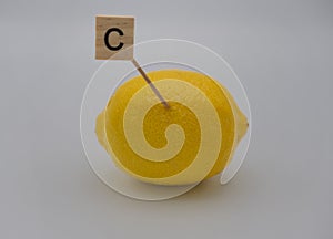 A letter C,over yellow lemon with a gray background. Concept of natural vitamins