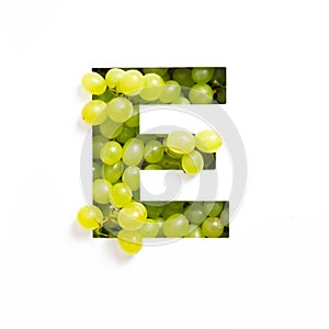 Letter E of English alphabet of green grape and cut paper isolated on white. Typeface made of fresh berries
