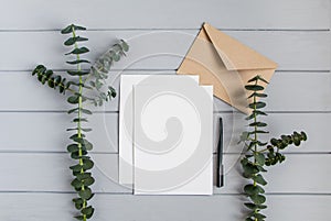 Letter, envelope and eucalyptus branches on grey background. Invitation card, or love letter. Top view, flat lay