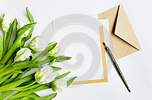 Letter, envelope and tulips on white background. Invitation card, or love letter. Top view, flat lay