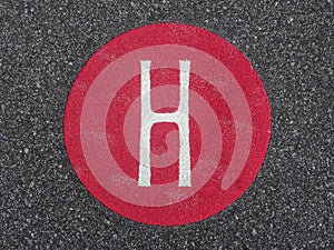 The Letter `H` in a Red Painted Circle on Pavement