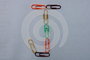 Letter J made with colorful paper clips on white background