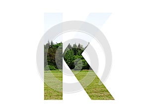 Letter K of the alphabet made with landscape with grass, forest and a blue sky