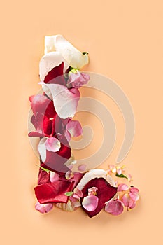 Letter L made from red roses and petals isolated on a white background