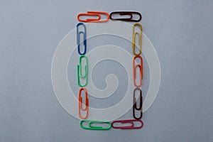 Letter O made with colorful paper clips on white background
