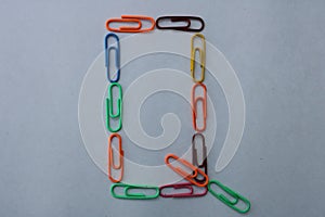 Letter Q made with colorful paper clips on white background