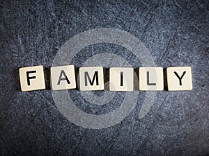 Letter tiles on black slate background spelling Family