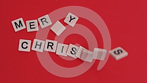 Letter tiles moving to spell out merry christmas on red background