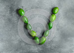 Letter V for vegan vegetables vitamins vitality made from ripe raw avocados on dark gray stone background. Food typography