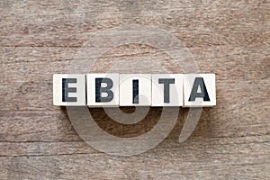 Letter in word EBITA abbreviation of earnings before interest, taxes and amortizationon wood background