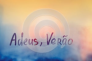 lettering Adeus Verao in Portuguese language is good bye summer in english on foggy glass on sunset window