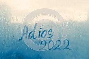 lettering Adios in Spanish is goodbye in english and numbers 2022 paint with finger of water on splashed by rain foggy