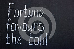 Lettering on a dark blackboard in white chalk fortuna favored the bold