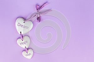 Lettering DREAM, HOPE, WISH on ceramic hearts on a lavender background. Concept for motivational postcard,