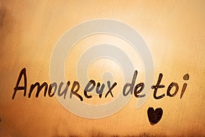 Lettering French text Amoureux de toi is In love with you in english with heart shape on orange sunset window photo