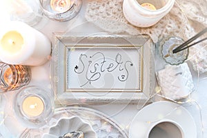 Lettering Inscription Sisters in white frame on shabby chic stylish background, feminity concept