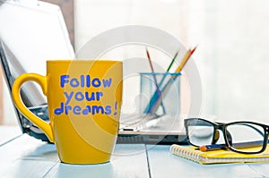 Lettering of inspirational quote Follow your dreams on yellow morning coffee or other hot drink cup at home, business photo