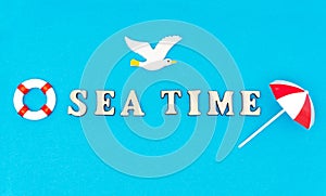 Lettering SEA TIME, seagull, lifebuoy and sun umbrella on blue background