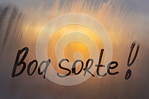 Lettering Spanish text Boa sorte Good luck in english message written finger on foggy glass wet sunset window photo