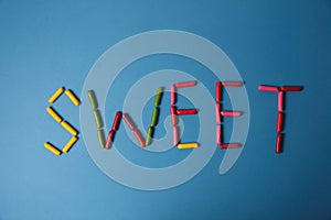 Lettering SWEET made of gumdrops  on blue background