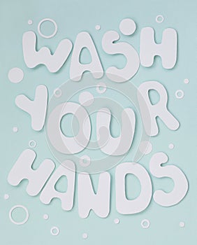 Lettering Wash Your Hands. White letters with soap bubbles on pastel light blue background.