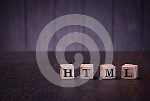 The letters abbreviation html on wooden cubes, on a dark background, light wooden cubes signs