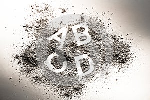 Letters a, b, c, and d written in grey ash, sand, filth or dust photo