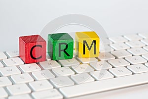 The letters CRM stand for Customer Relationship Management. These letters are written in black on red, green and yellow blocks and