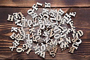 Letters of the English alphabet on a dark wooden background. The concept of education, word games, needlework.