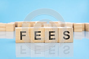 letters FEES made with wood building blocks. blue background. business concept