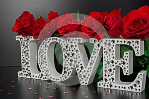 Letters Love on black background with red roses