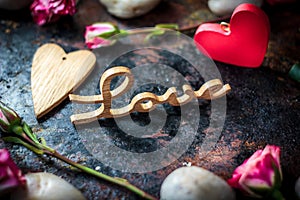 Letters LOVE on rustic background with hearts and flowers