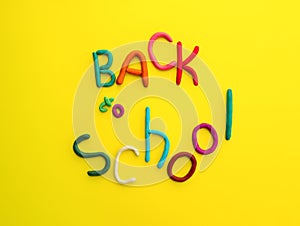 letters made of multi-colored plasticine back to school in wry funny style on yellow background