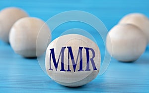 The letters MMR are depicted on a wooden round ball on a blue background