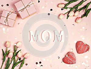 Letters MOM with gifts, tulips and hearts on a pink background
