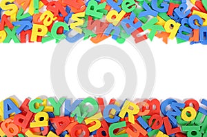 Letters of plastic toy alphabet border on white background, copy space