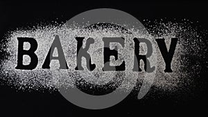 Letters of word bakery made with sieved flour on black table background, Preparation for baking, horizontal banner, Lettering