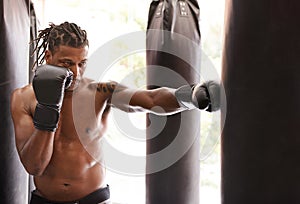 Letting it all out. a young boxer practicing on a punching bag in a gym.