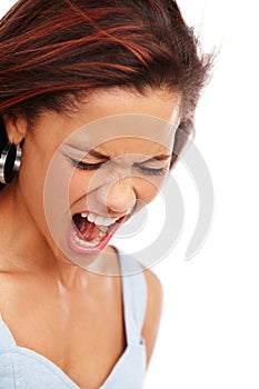 Letting it all out. A young woman screaming loudly while isolated on a white background.