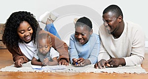 Letting his creativity run wild. a two young parents lying on the living room floor with their children and watching